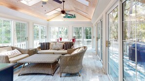 A sunroom with wicker furniture, a ceiling fan, and a sign that reads "Beach". - Seabrook Exclusives | 2717 Seabrook Island Rd (Seabrook Island)