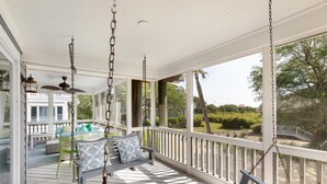A covered porch with a swing, a table, and chairs. - Seabrook Exclusives | 2248 Rolling Dunes (Seabrook Island)