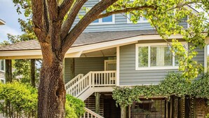 A two-story house with a covered porch and a staircase leading to the second floor. - Seabrook Exclusives | 2248 Rolling Dunes (Seabrook Island)