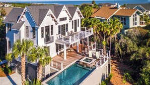 Une grande maison avec une piscine, plusieurs terrasses et une vue sur l’océan.