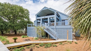 Una casa moderna azul con un porche cubierto y una terraza de madera.