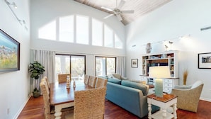 Un salón comedor espacioso con techo alto, ventanas grandes y una zona de estar acogedora.