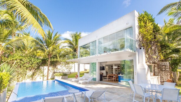 A modern house with a swimming pool, white outdoor furniture, and lush greenery. - Casa da Árvore - com piscina privativa em Pipa por Carpediem (Tibau do Sul)