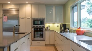 Een moderne keuken met roestvrijstalen apparatuur, witte kasten en een raam dat voor natuurlijk licht zorgt.
