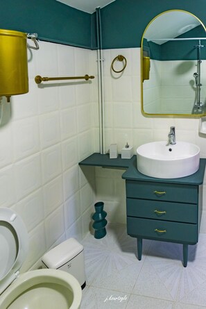 Bathroom features a white toilet, sink with gold faucet, and a mirror above the sink.