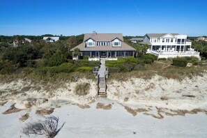 A beachfront property with a large house, a covered walkway, and surrounding vegetation.