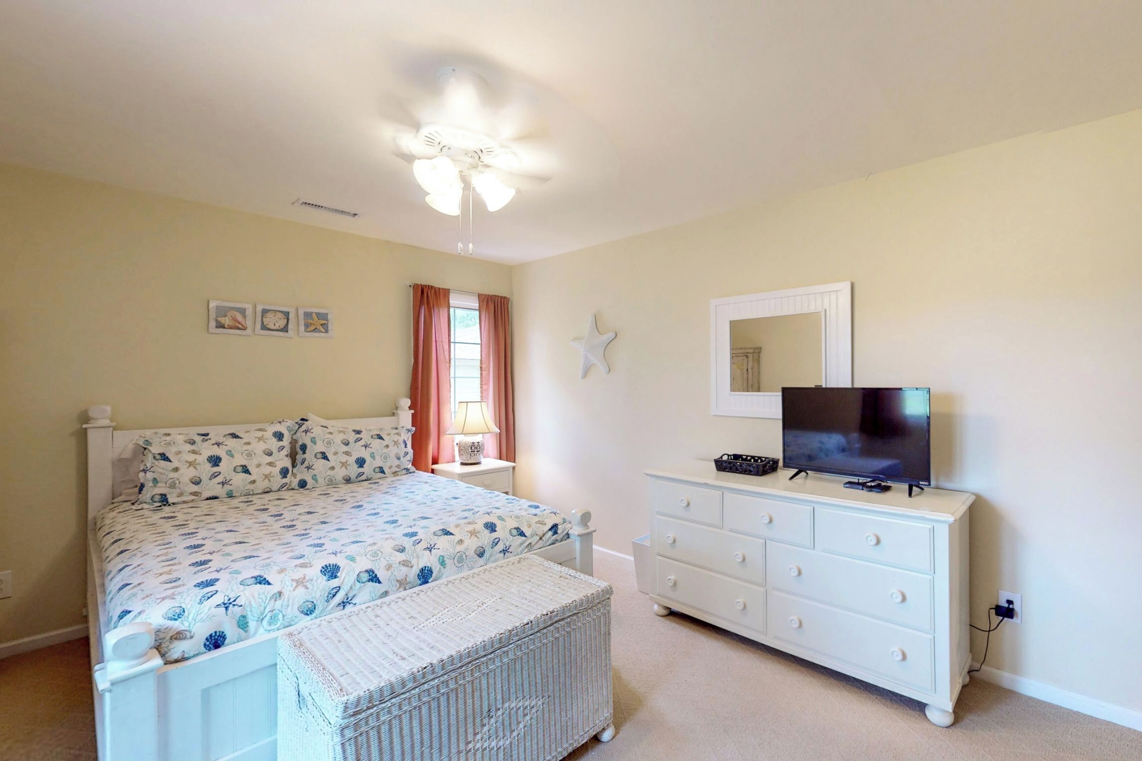 A bedroom with a bed, a dresser, a television, and a ceiling fan.