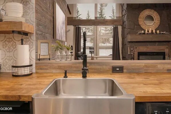 Enjoy cooking in this well-equipped kitchen with a central sink, ample countertop space, and a fireplace.