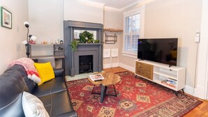 Una sala de estar con chimenea, un sofá, un televisor y un ventilador de techo.