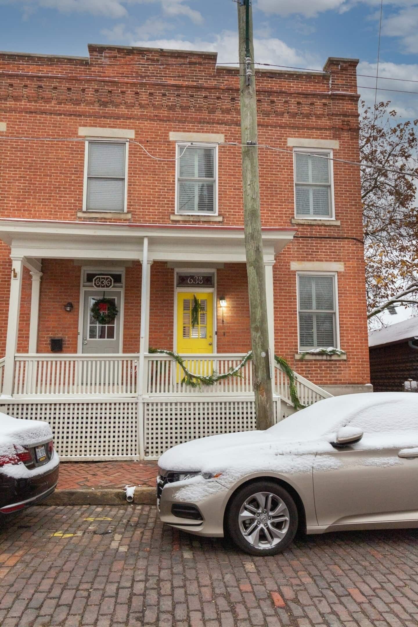 A two-story brick building with a yellow door and a white picket fence.
