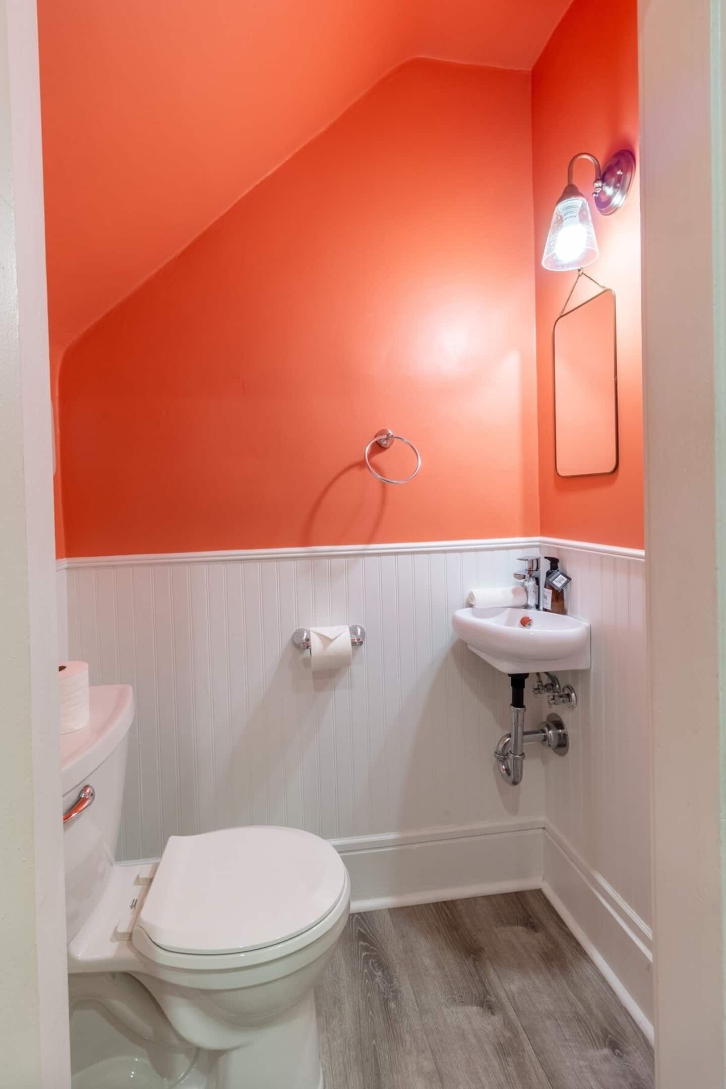 Un baño con inodoro y lavabo blancos, y ducha con pared blanca.