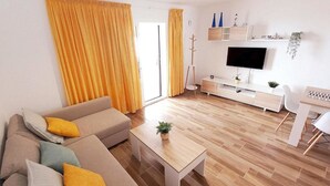 Un salon moderne avec un canapé, une table basse et un téléviseur.