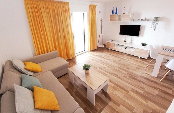 Ein modernes Wohnzimmer mit einer Couch, einem Couchtisch und einem Fernseher.