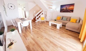 Ein modernes Wohnzimmer mit Treppe, Essbereich und einer Couch mit Kissen.