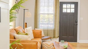 A living room with a sofa, a coffee table, and a door. - The Modern Historic Gem | Just minutes to Downtown (West Columbia)