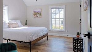 A bedroom with a bed, a ceiling fan, a window, and a small table with a plant. - The Modern Historic Gem | Just minutes to Downtown (West Columbia)