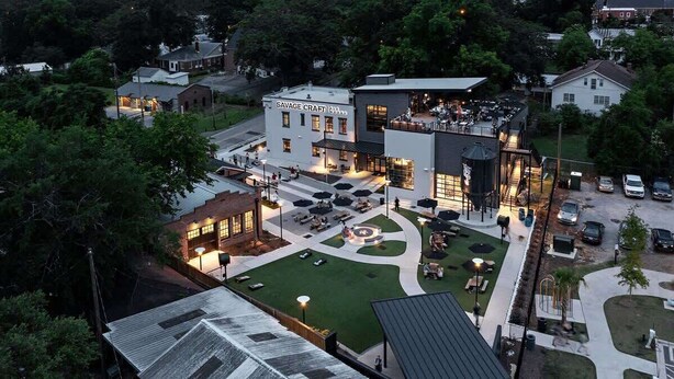 A modern building with a sign reading "SAVAGE CRAFT." It features outdoor seating areas, a central courtyard, and a well-maintained lawn. - The Modern Historic Gem | Just minutes to Downtown (West Columbia)