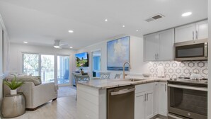Cozinha moderna com ilha central, eletrodomésticos de aço inoxidável e área de jantar com vista.