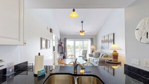 Una cucina moderna con un'isola grande, lavelli in acciaio inossidabile e una ventola a soffitto.