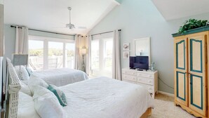 Una camera da letto con due letti, un ventilatore a soffitto, una TV e un armadio.