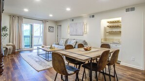 A spacious living area with a dining table, chairs, a sofa, and a kitchen area with a wine rack. - Seabrook Exclusives | 2011 Marsh Walk (Seabrook Island)