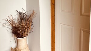 Una porta blanca amb un rètol de "Welcome", un vas amb plantes seques i una presa de corrent a la paret.