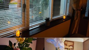 Una habitació amb una finestra, una taula amb un ram de flors i una espelma.