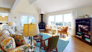 Uma sala de estar aconchegante com sofá, cadeiras, uma mesa, abajur, lareira e televisão.
