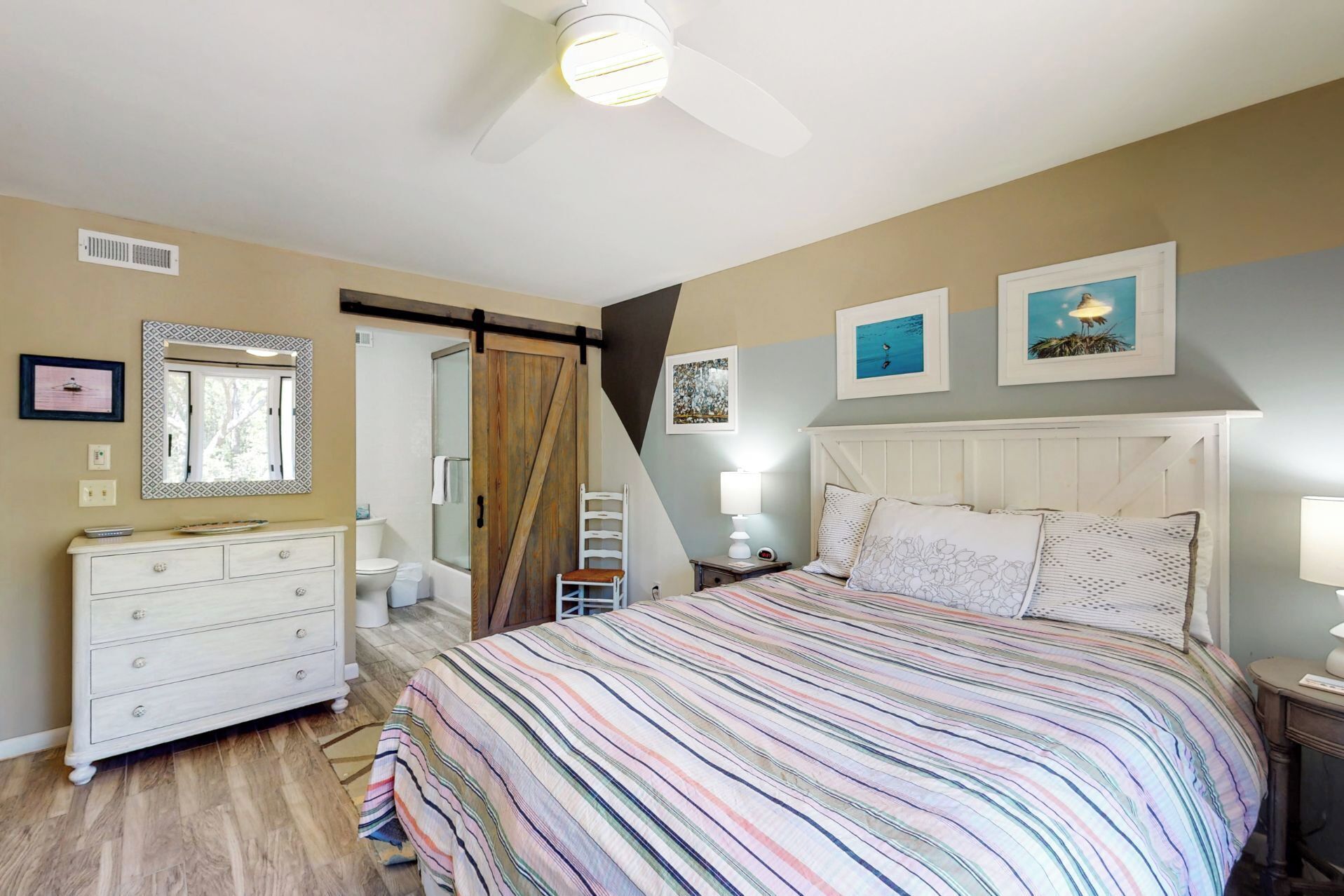 Un dormitorio con cama, cómoda, tocador, ducha y ventilador de techo.