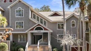 A two-story house with a front porch, a staircase, and a garage. - Seabrook Exclusives | 2764 Live Oak Villa (Seabrook Island)