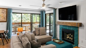 A living room with a sofa, a fireplace, and a TV mounted on the wall. - Seabrook Exclusives | 2764 Live Oak Villa (Seabrook Island)
