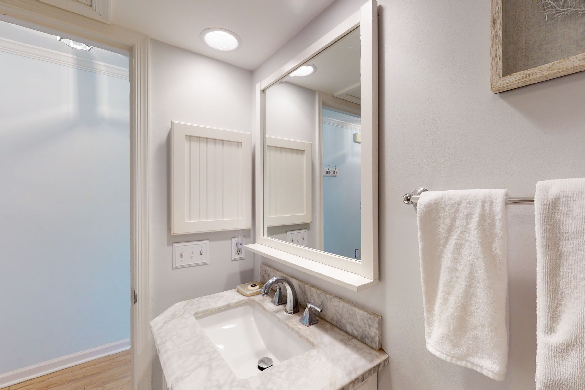 A bathroom with a white sink, a mirror, and a towel rack.