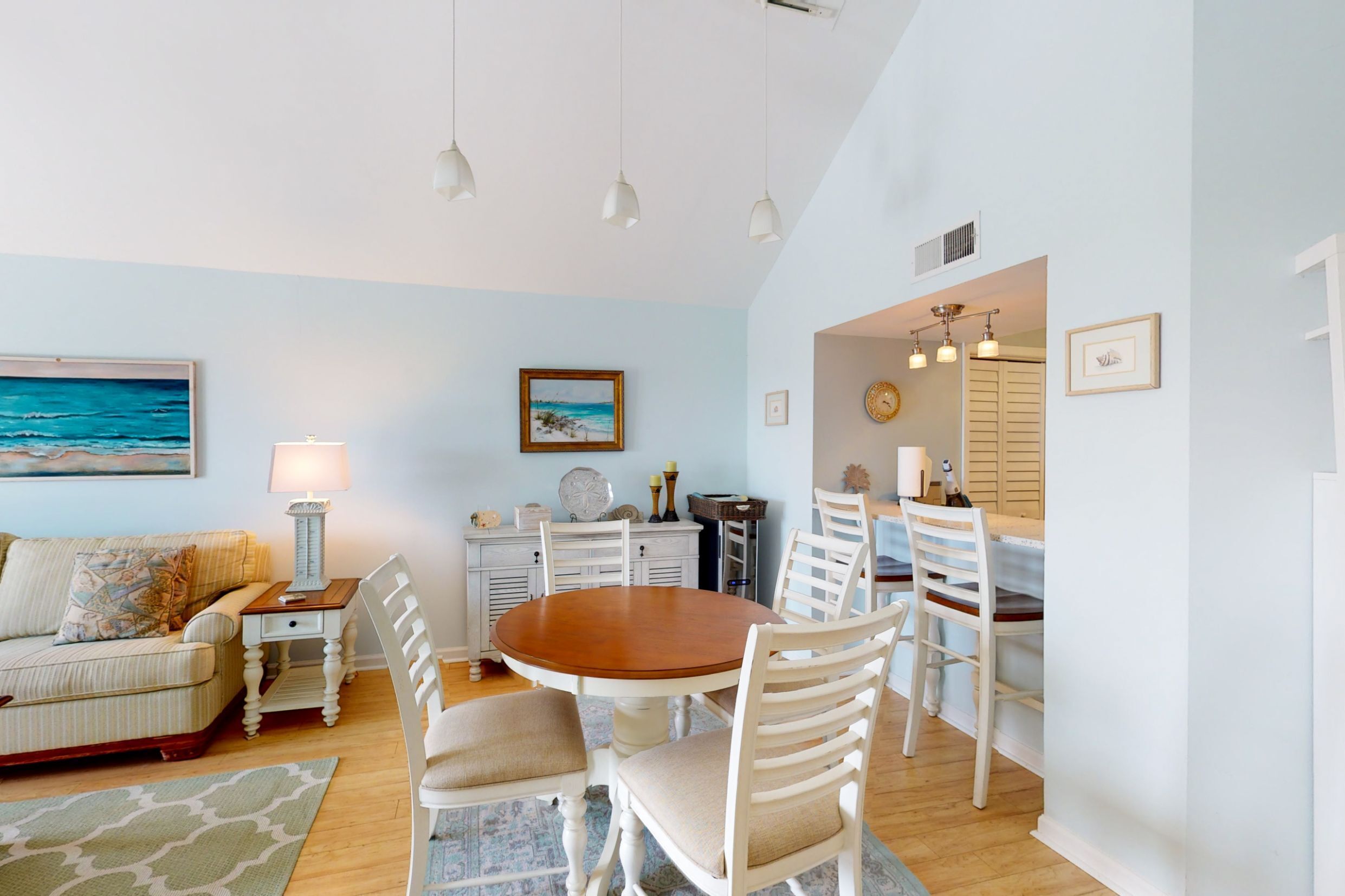 A dining area with a round wooden table, white chairs, and a white cabinet with a clock.
