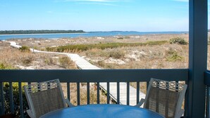 Ein Balkon mit Korbstühlen mit Blick auf einen Strand und einen Promenadenweg.