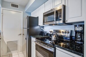 Enjoy cooking in this well-equipped kitchen with a refrigerator, microwave, stove, and coffee maker.