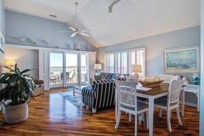 Relax in this inviting living area with a high ceiling, ceiling fan, and large window with blinds.
