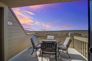 Enjoy the ocean view from this balcony with a table and two chairs.