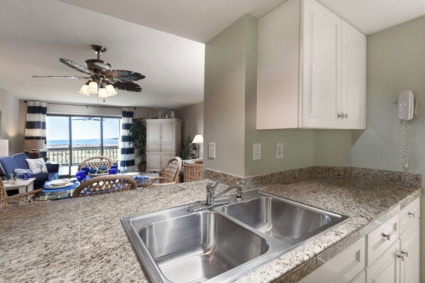 A kitchen with granite countertops, stainless steel sinks, and white cabinets.