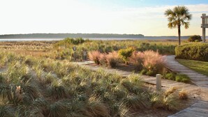 Une promenade en bois traverse une zone herbeuse, et des panneaux indiquent « Week-end » et « Accès interdit ».