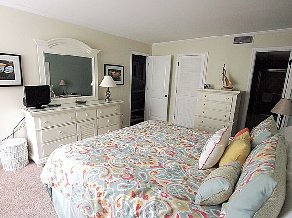 Un dormitorio con una cama grande, un aparador, un televisor y un espejo.