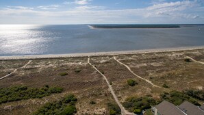 An aerial view of a coastal area with a sandy beach, a small island, and a clear sky. - Seabrook Exclusives | 1387 Pelican Watch (Johns Island)