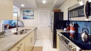 A modern kitchen with stainless steel appliances, a double sink, and a microwave. - Seabrook Exclusives | 1387 Pelican Watch (Johns Island)