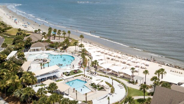 A resort with a large pool area, beach access, and palm trees.