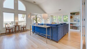A spacious living area with a blue sofa, a dining table with chairs, and a kitchen island.