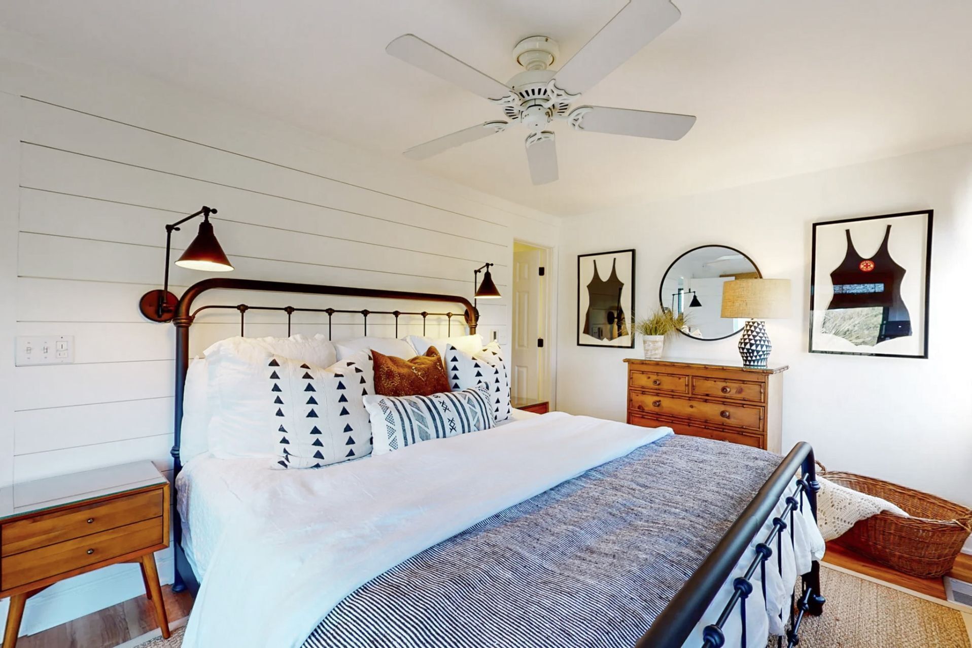 A bedroom with a bed, bedside tables, a dresser, a ceiling fan, and wall art.