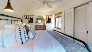Un dormitorio con cama, cómoda, espejo y ventilador de techo.