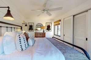 Ein Schlafzimmer mit Bett, Schminktisch, Spiegel und Deckenventilator.