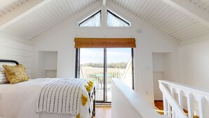 Un dormitorio con cama, ventana con vistas y balcón.