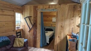 Ein Holzblockhaus mit einem Bett, einem kleinen Tisch und einem Stuhl.