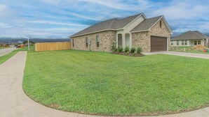 A single-story house with a brick exterior, a garage, and a well-maintained lawn. - Cozy NEW Home in the Heart of Lafayette! (Lafayette)